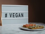 © Tima Miroshnichenko_Pexels Teller mit Broten, dahinter Aufschrift vegan