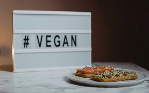 © Tima Miroshnichenko_Pexels Teller mit Broten, dahinter Aufschrift vegan