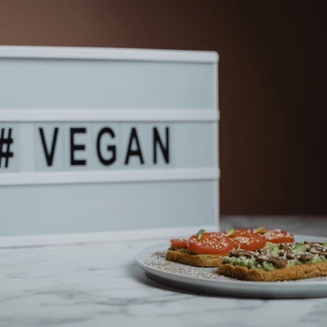 © Tima Miroshnichenko_Pexels Teller mit Broten, dahinter Aufschrift vegan