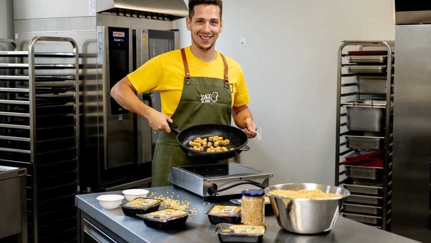 Unternehmensgründer Hannes Weichhart präsentiert frisch gebratene Tempeh-Würfel in einer Pfanne