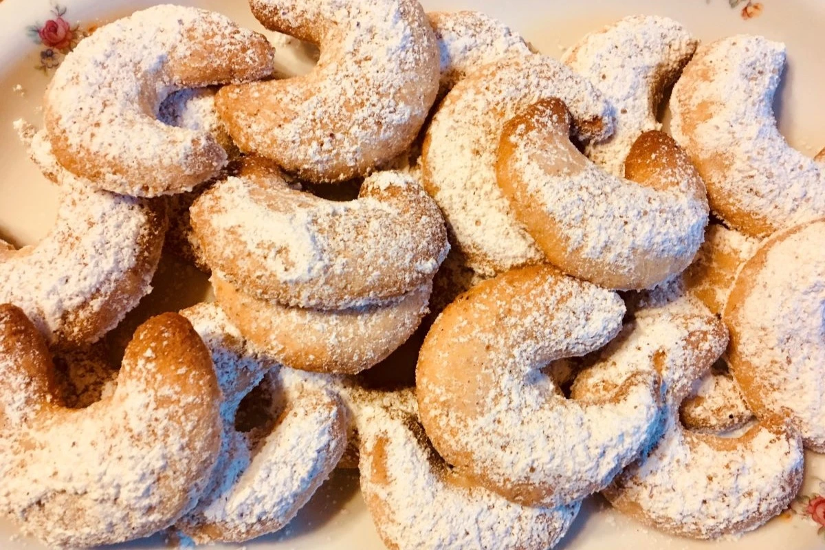 ein Teller mit Vanillekipferln, die in Staubzucker gewälzt wurden