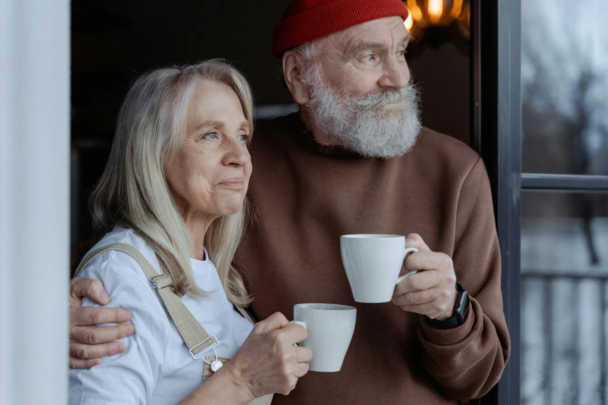 Eine Frau und ein Mann im reifen Alter mit Kaffeebechern in der Hand zum rechten Bildrand schauend