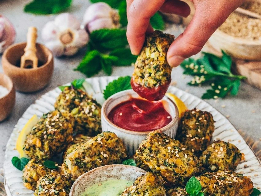 Brokkoli-Käse-Nuggets, die in einen Dip getunkt werden.
